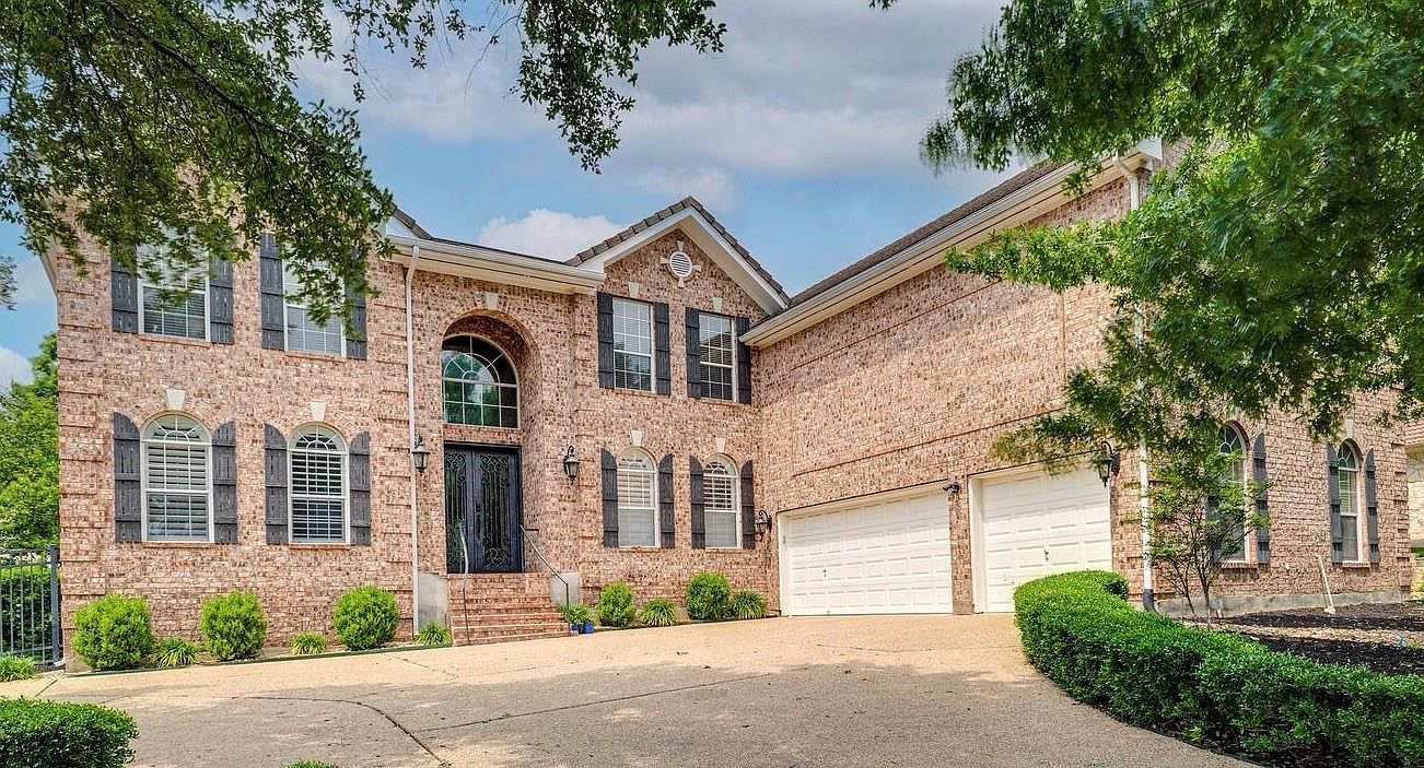 Front elevation of 14 Torrington Ln showing the two-story brick facade, arched entry, and three-car garage