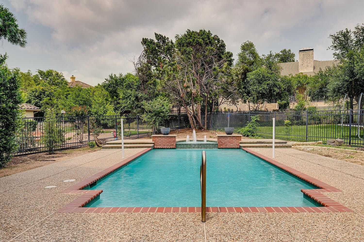 Sparkling rectangular pool framed by mature oaks and brick coping at 14 Torrington Ln