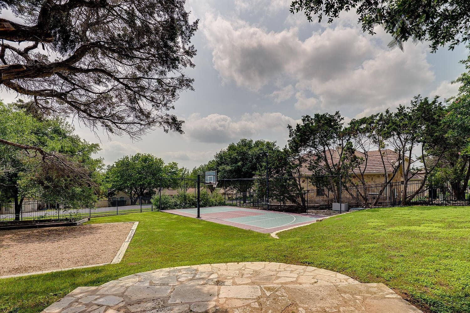 Aerial view of 14 Torrington Ln showing the brick estate, sport court, mature oaks, and the full double lot behind a gated cul-de-sac in The Hills