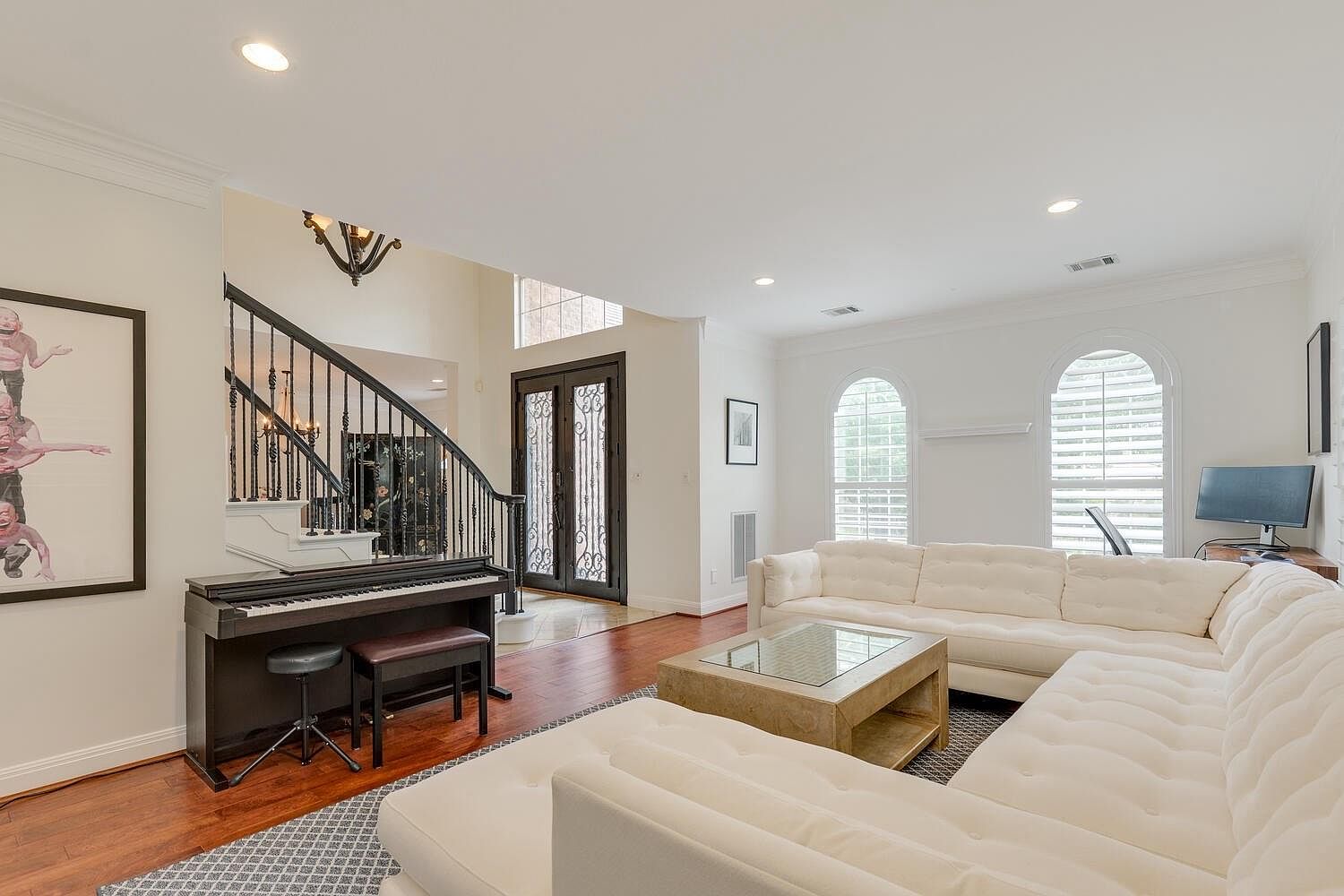 Two-story foyer with curving wrought-iron staircase, ornate iron-and-glass front doors, and hardwood floors